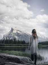 woman standing near rock in front of lake